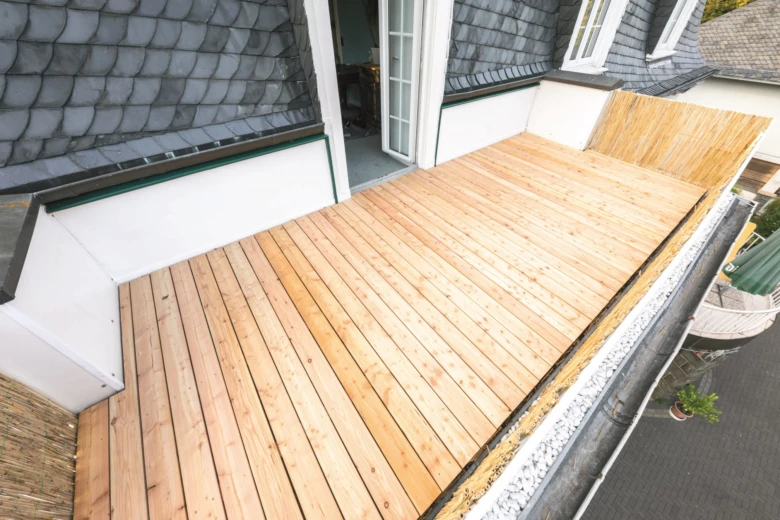 Nová dřevěná terasa na balkónu s viditelnou hydroizolací podél stěny.