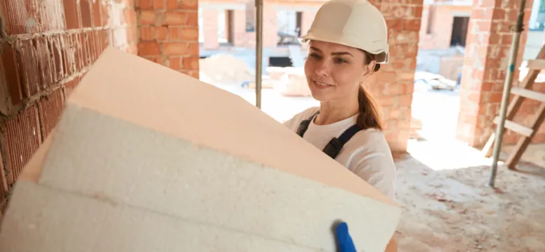 Žena drží desky z expandovaného polystyrenu ve stavbě.