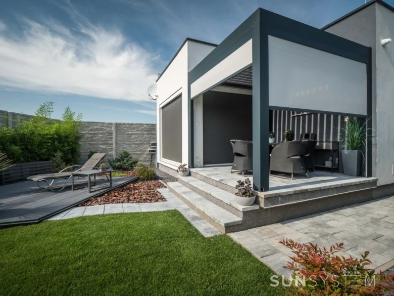 Moderní hliníková pergola s rolojmy v zahradě moderního domu.