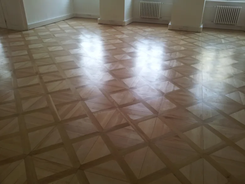 Opravená parketová podlaha po renovaci v prázdné místnosti.