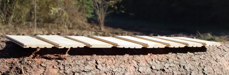 Světlé dřevěné podlahové palubky položené na kmeni stromu venku.