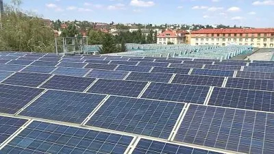 Fotovoltaické panely na střeše budovy v městském prostředí.