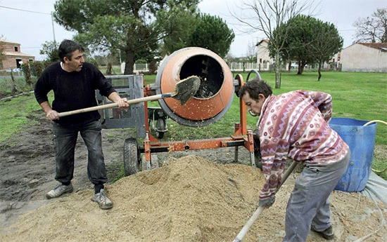 Dva muži míchají zdivní maltu pomocí betonu smíchavače.