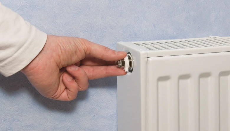 Ruka odšrouvává víčko odvzdušňovacího ventilu na radiátoru.