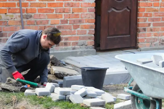 Muž klade betonové dlaždice u základů domu.