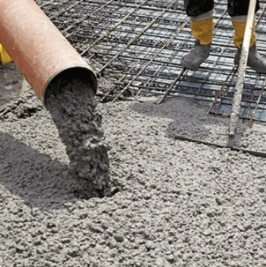 Svěží beton se nalévá na ocelovou výztuž při stavbě.