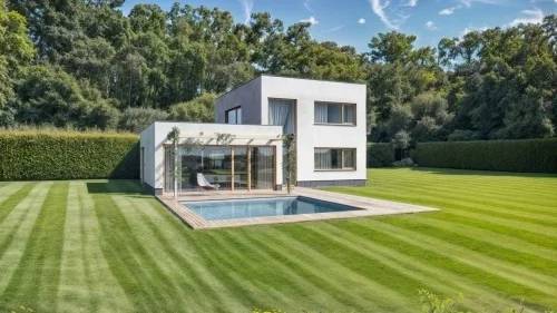 Moderní luxusní dům s bazénem uprostřed zelené zahrady.