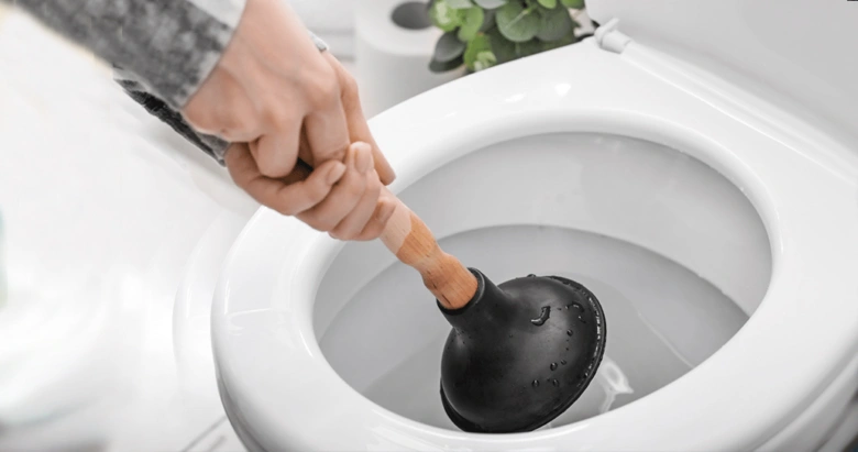 Ruka s hadicí uvolňuje ucpaný záchod.