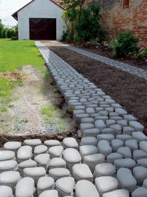 Nově položená zatravňovací dlažba z betonových kostků vedle trávníku.