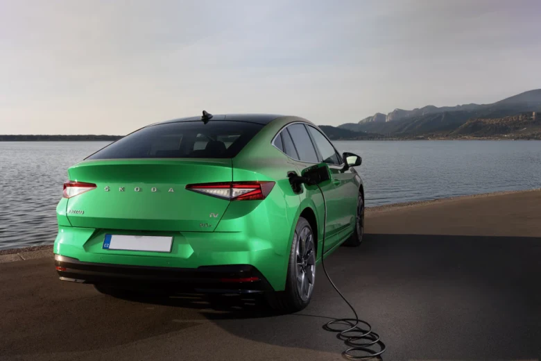 Zelené elektromobilové auto nabíjené u jezera.