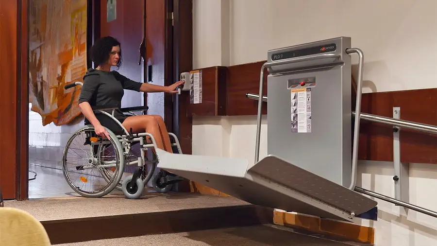 Žena v invalidním vozíku používá schodišťovou plošinu.