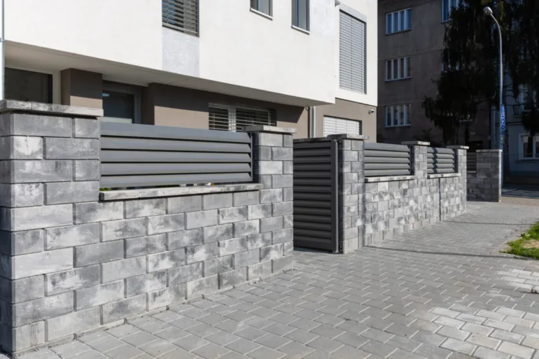 Moderní plot z betonových tvarnic s horizontálními lištami.