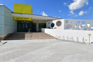 Moderní krytý plavecký bazén s výraznou žlutou architekturou.