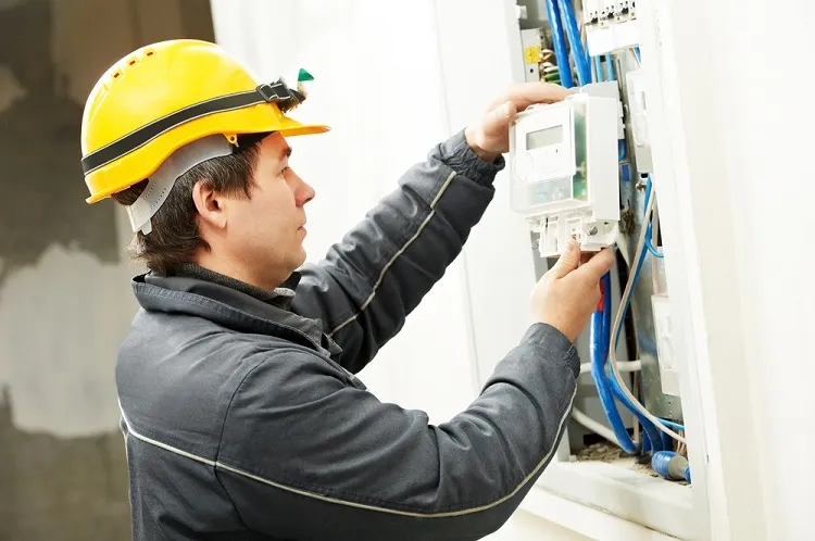Elektrikář pracuje na rozvaděči s viditelným zapojením kabelů.
