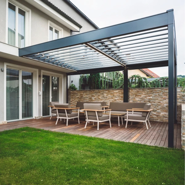 Moderní kovová pergola s venkovním sedákem připojená k domu.