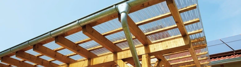 Pergola s plastovou střešní krytinou na dřevěném nosníku.