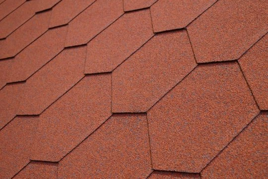 Detail červených střešních šindelů na skloněné střechy.