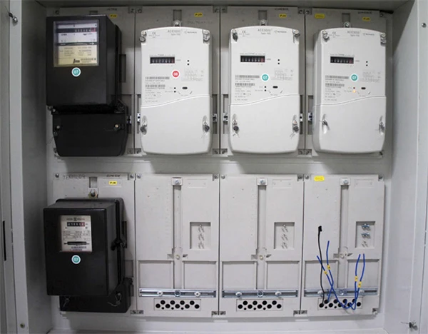Vnitřek elektroměrového rozvaděče s měry a prázdnými zásuvkami pro jističe.