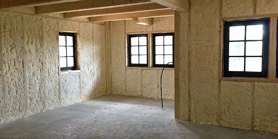 Vnitřní stěny budovy zateplené bílou stříkanou izolací.
