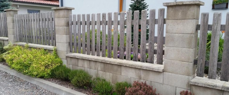 Moderní betonový plot s dřevěnými prkny a kvetinovou výsadbou.