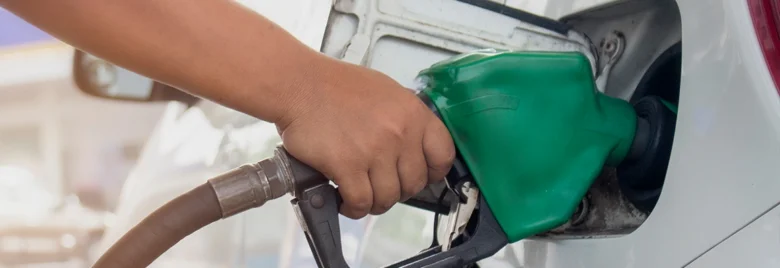 Ruka s čerpadlem doplňuje benzín do auta na benzinové stanici.