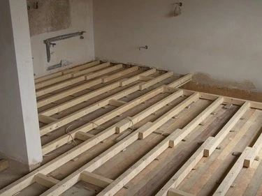 Dřevěné trámy pro podlahu v interiéru při stavbě.