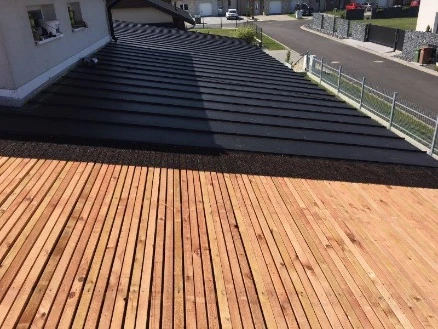 Moderní plechová střecha s dřevěnou terasou u domu.