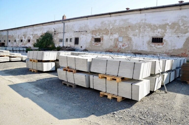 Skládané betonové panely na paletách u průmyslového objektu.