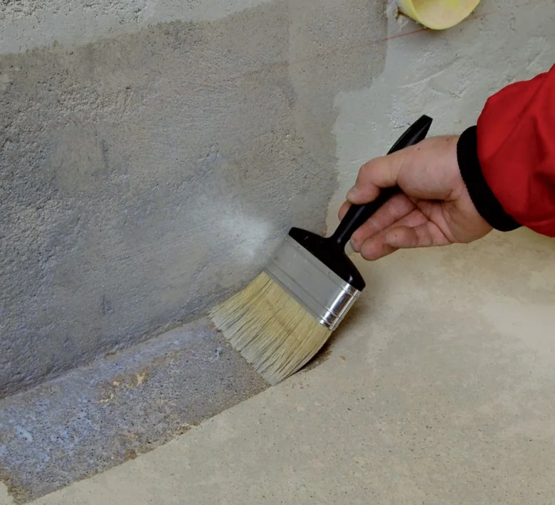 Nápis tekuté hydroizolace na betonovou stěnu štětcem.