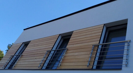 Moderní dřevěné obložení fasády s kovovým zábradlím na balkóně.