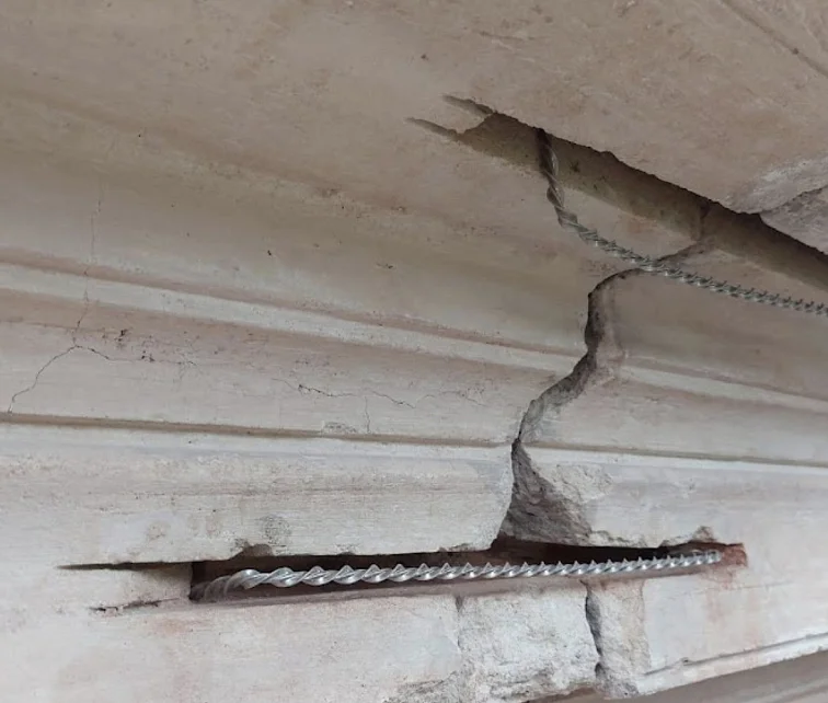 Helikální výztuž viditelná v prasklém kamenném nebo betonovém prvku.