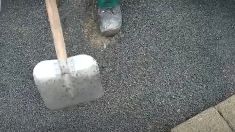 Štěrka pod zámkovou dlažbu s lopatou na povrchu.