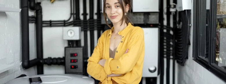 Žena stojí v místnosti s elektrickým kotlem pro vytápění domácnosti.