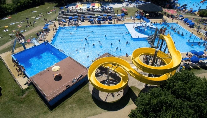 Vodní park s bazénymi a žlutými vodními skluzavkami.