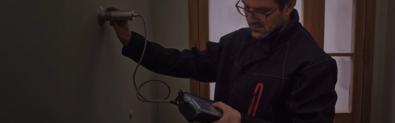 Muž kontroluje stav zdiva pomocí elektronického měřicího přístroje.