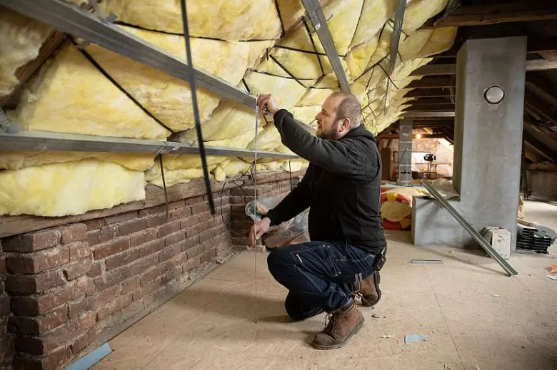 Muž měří rastr na sádrokarton v podkroví pomocí provázku.