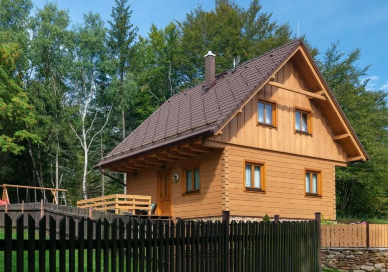 Moderní dřevěný dům s plotem uprostřed lesa