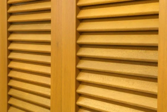 Detail dřevěných venkovních okenic s lamelami na okně.