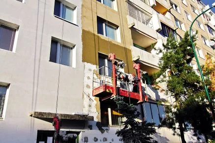 Práce na izolaci fasády pomocí polystyrenu u bytového domu.
