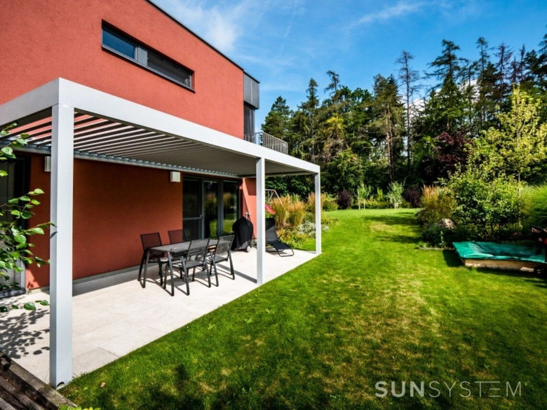 Bioklimatická pergola s venkovním posezením u domu v zahradě.