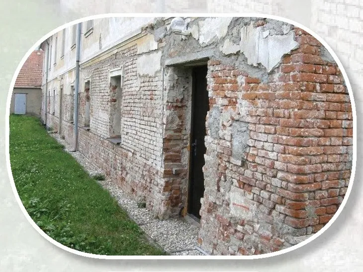 Zchátralá fasáda s odlupující se omítkou a viditelnými cihlami.