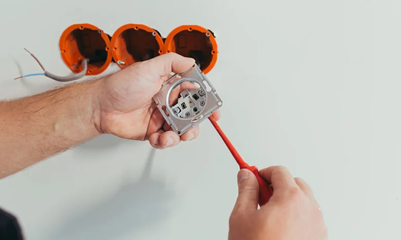 Instalace elektrické zásuvky do zdi s viditelnými vodiči.