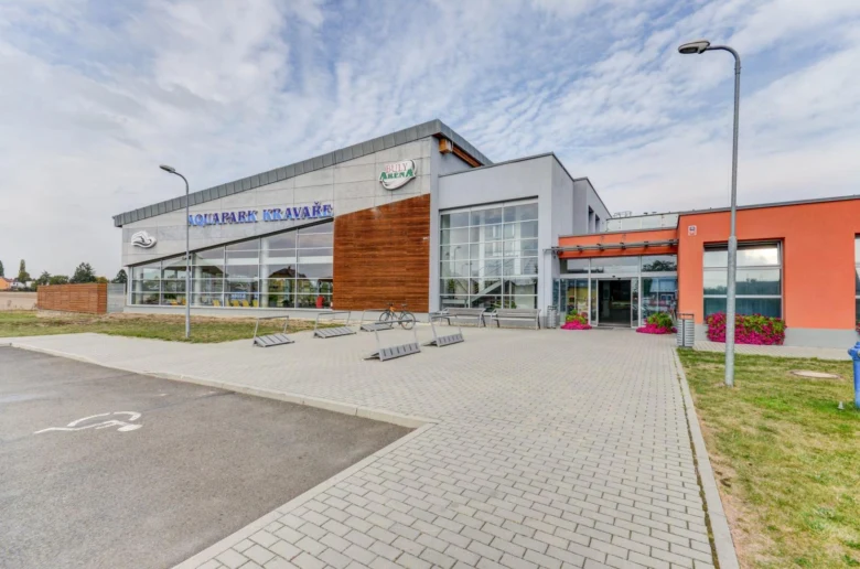 Vstupní část bazénu v Kravařích s parkovištěm před budovou.