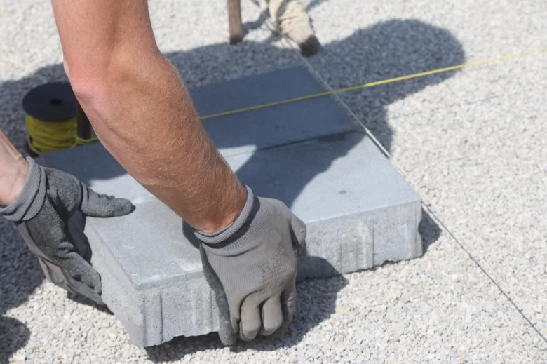 Ruční pokládka betonové dlažby na štěrkovém podkladu.