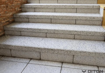 Venkovní betonové schody vedoucí k vchodu s cihlovým zděním.