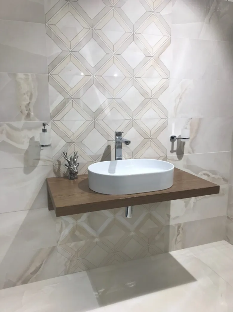 Moderní koupelna s mramorovými stěnami, dřevěnou umyvadlovou deskou a geometrickým dlaždicovým vzorem.