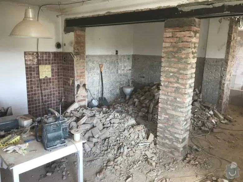 Demolice starého domu s odhalenými cihlovými sloupy.