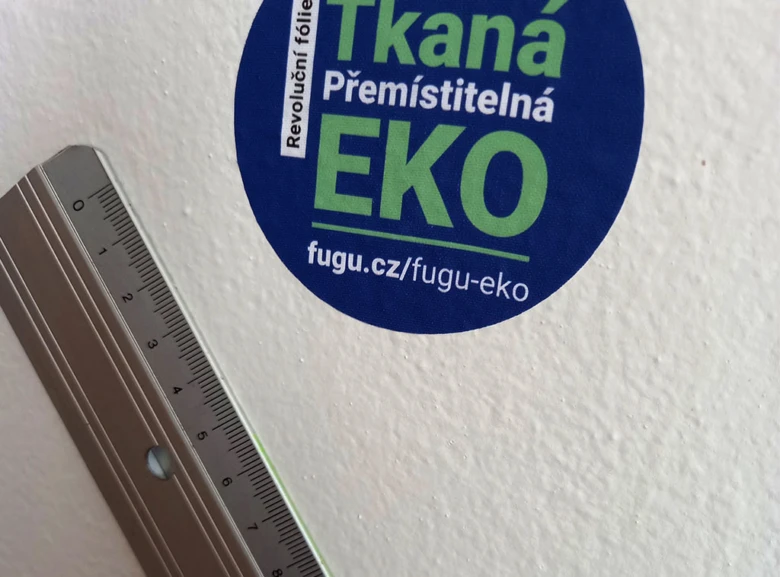 Modrá samolepící tapeta na zdi s měřicí páskou vedle ní.