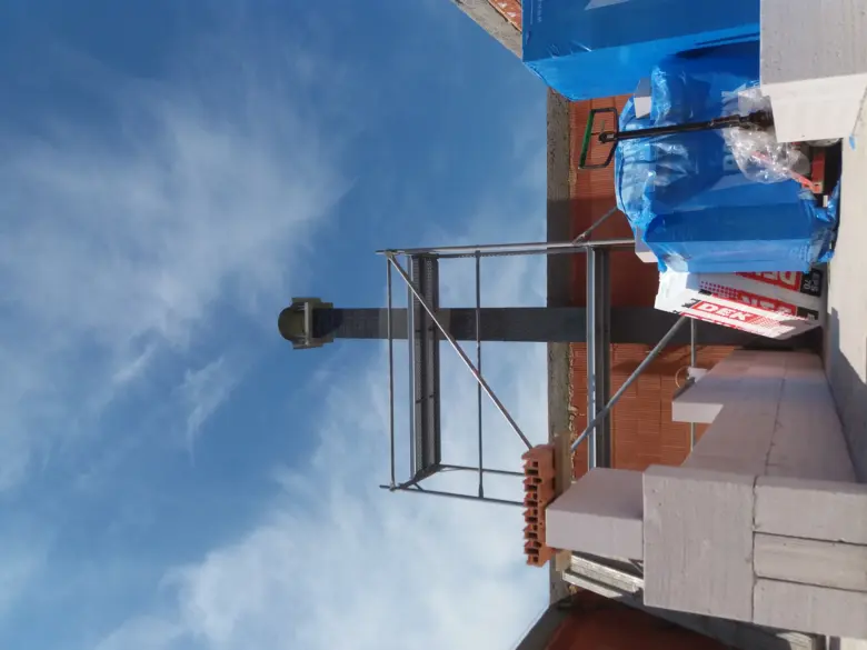 Stavba komína na střeše s lešení a materiály.