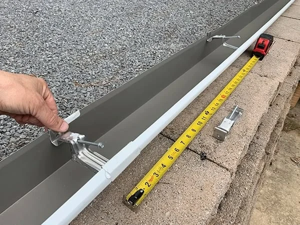 Montáž okapového háku na střešní svah s měřicím pásmo.